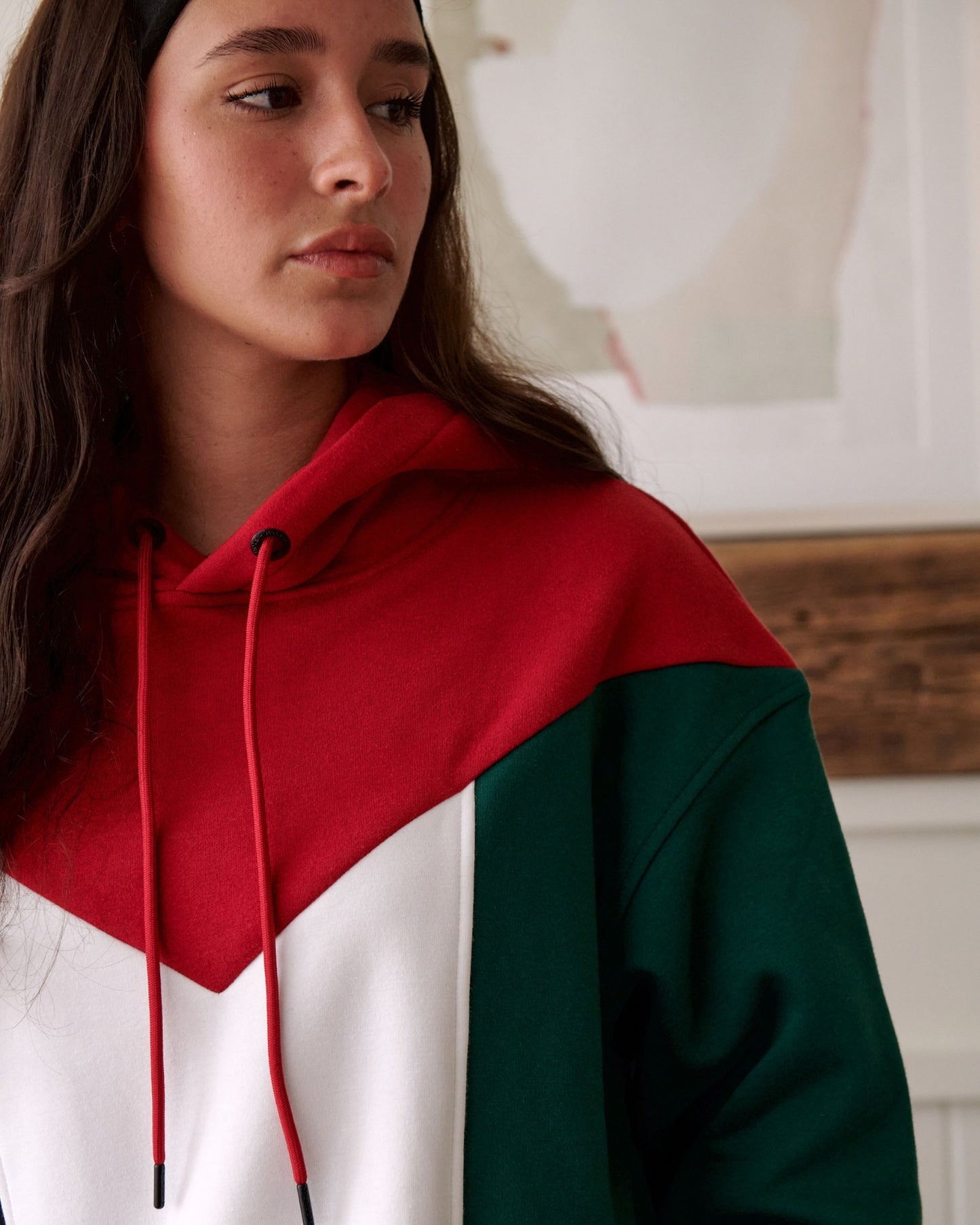 Close-up of a young woman wearing a red, white and green hoodie with a string.
