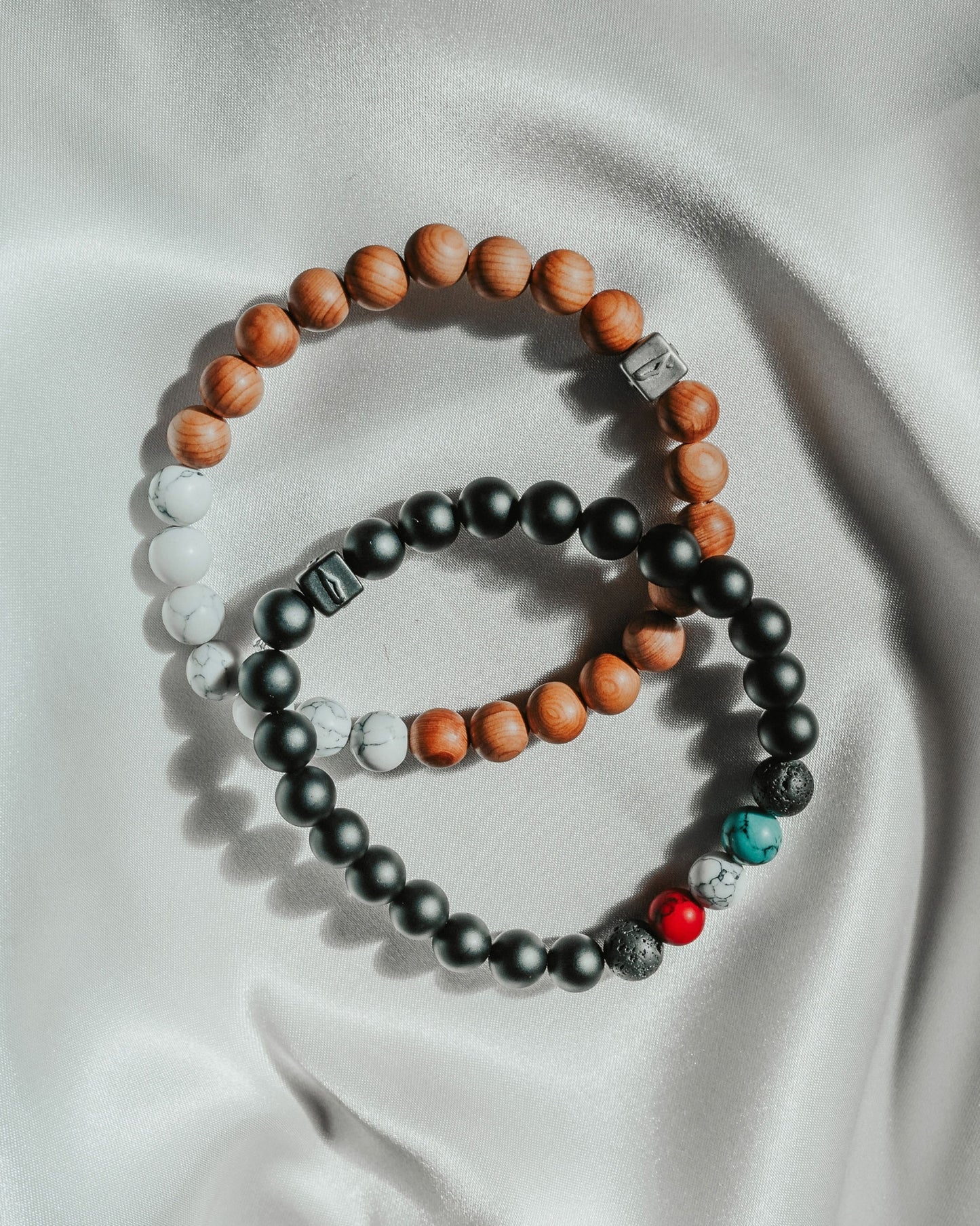 Two bracelets featuring wooden beads alongside red and black beads, showcasing a blend of natural and vibrant colors, highlighting a stylish and earthy design.