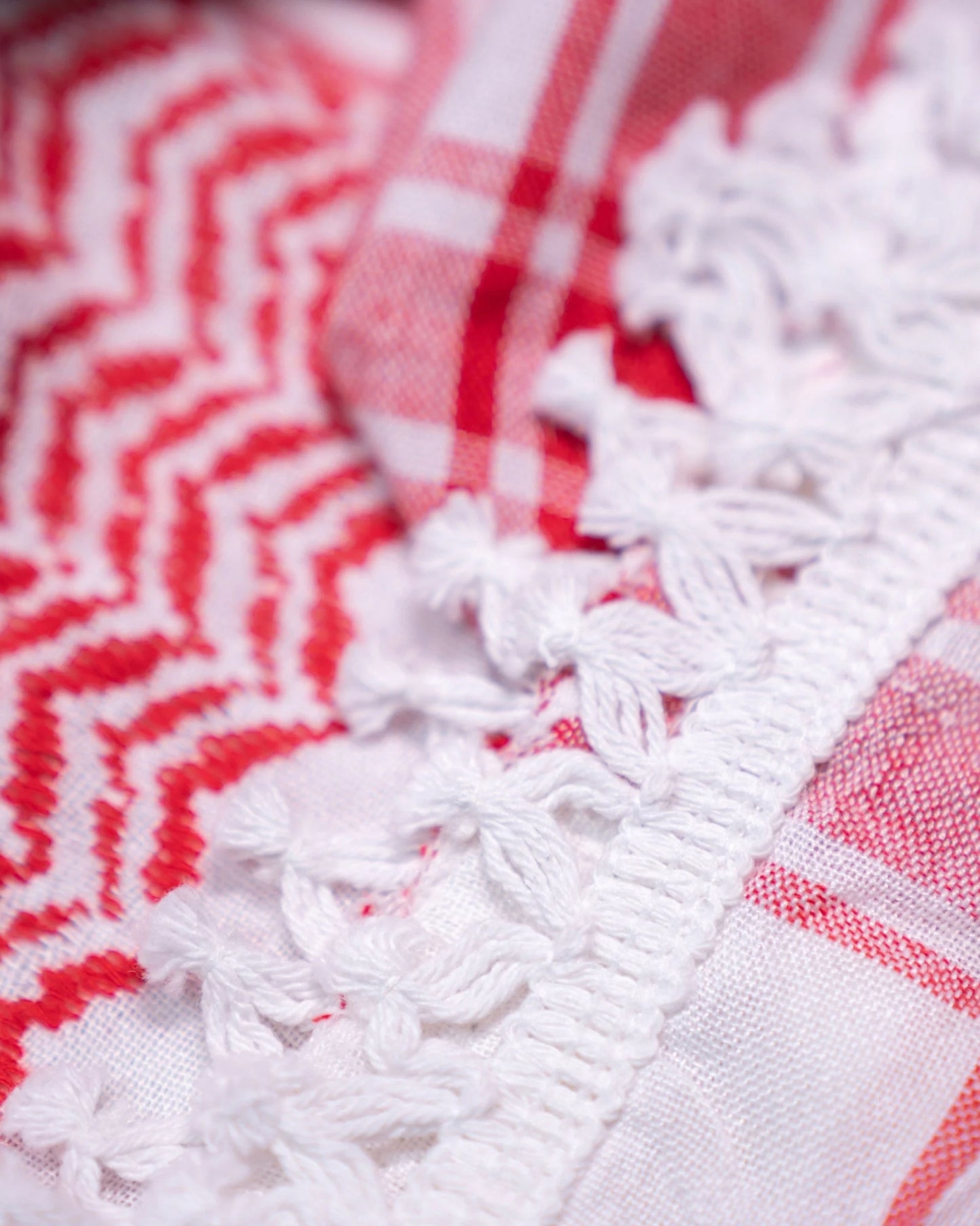 Close-up of the edges of a red and white scarf, showcasing its fabric texture and vibrant red color, emphasizing its rich hues.